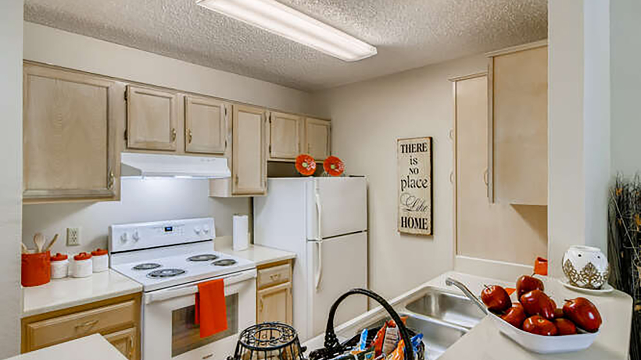 apartment kitchen with electric stove top oven, refrigerator, and sink