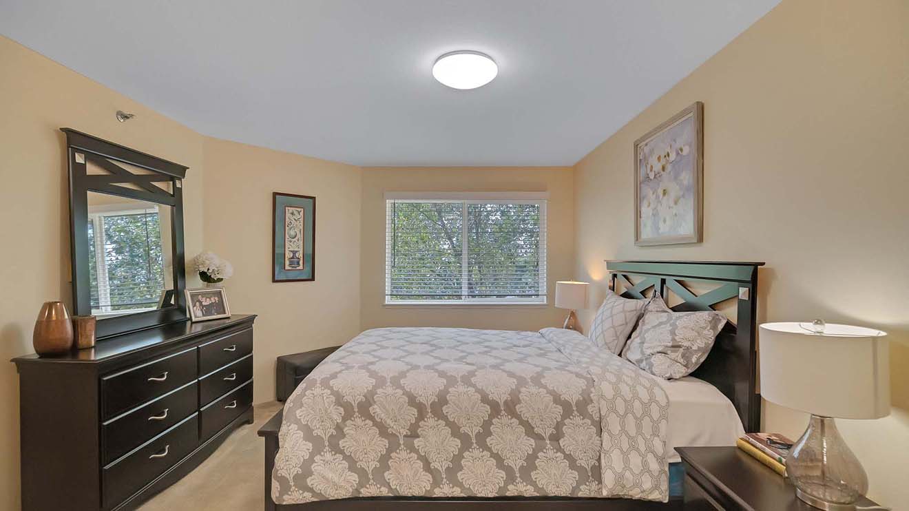 Retirement home bedroom in Manassas, VA with window, overhead lighting and space for dresser, bed and side tables.