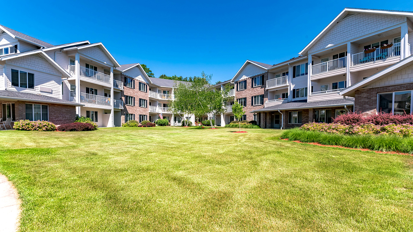 Outdoor view of Middleton, WI retirement community with lush greenery, patios and balconies at Holiday Middleton.