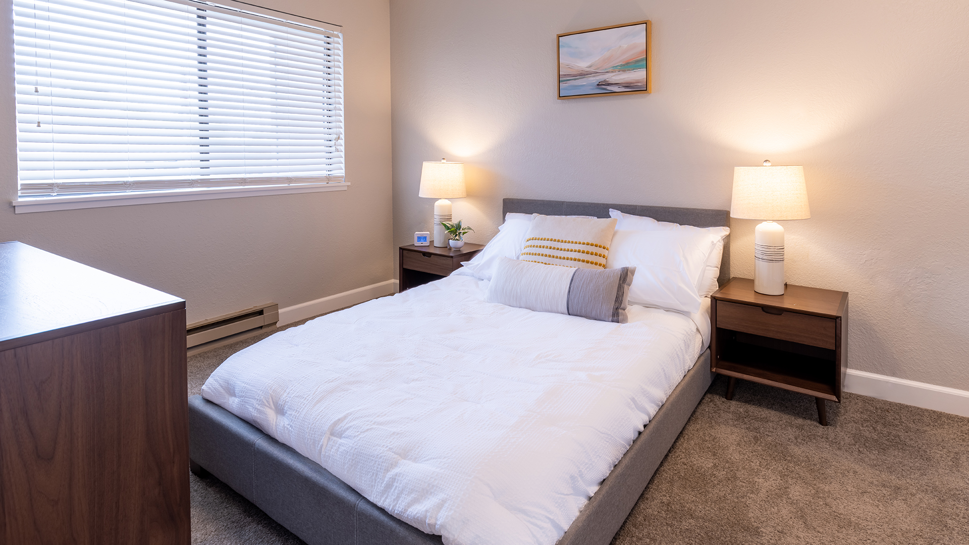 Cozy senior apartment at Holiday Virginian with window and carpeting in a furnished bedroom.